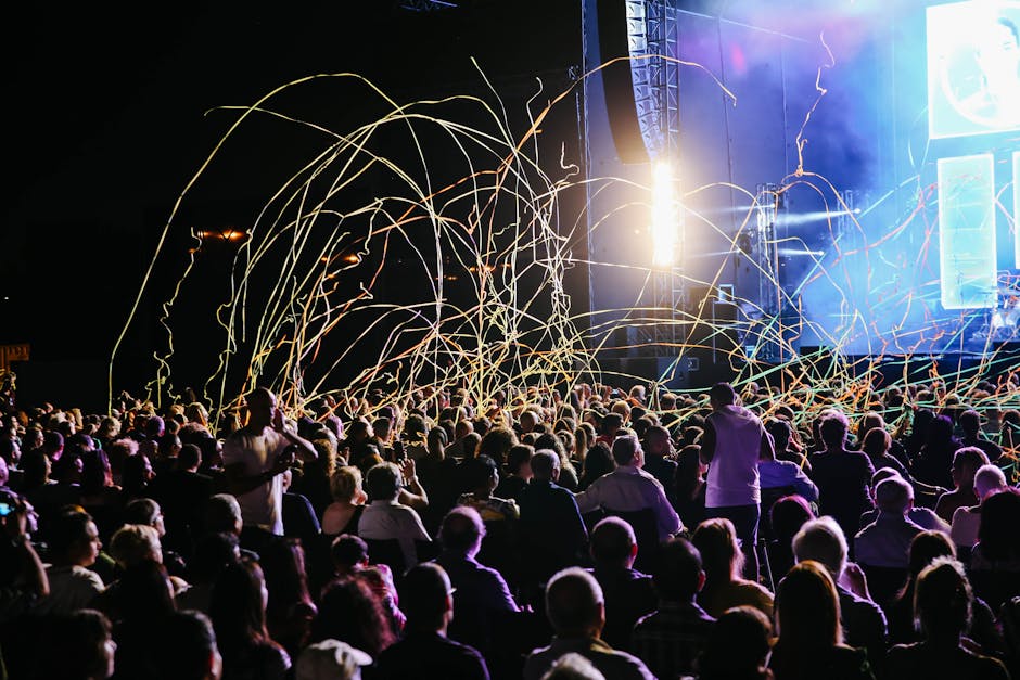 Exciting nighttime concert scene with a lively crowd and colorful streamers.