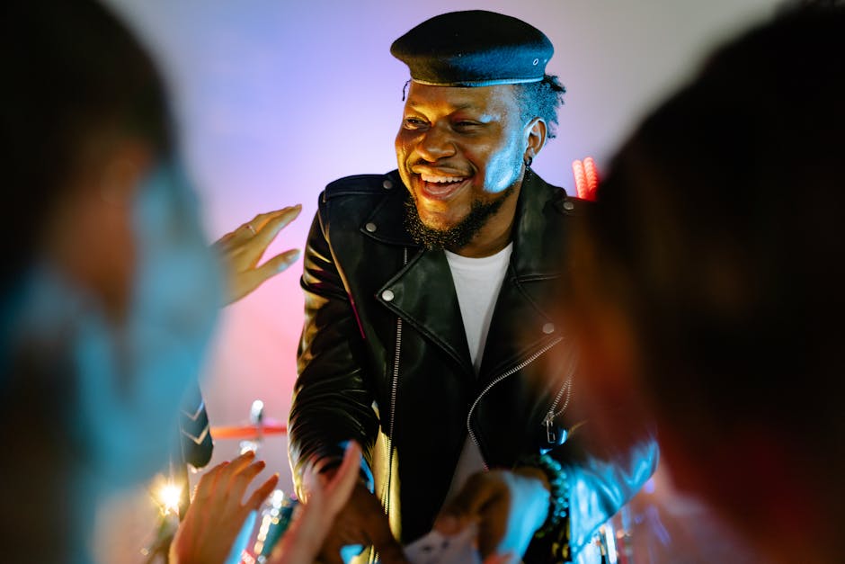 Dynamic photo of a smiling musician wearing a black beret and leather jacket on stage.