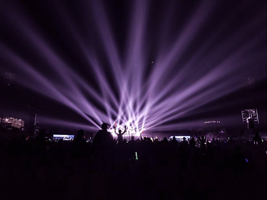 A lively night concert with beams of colorful lights and an energetic crowd.