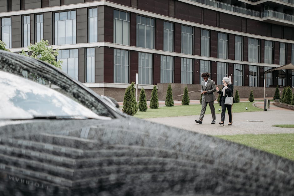 Two business professionals walking together outside a modern office building on a cloudy day