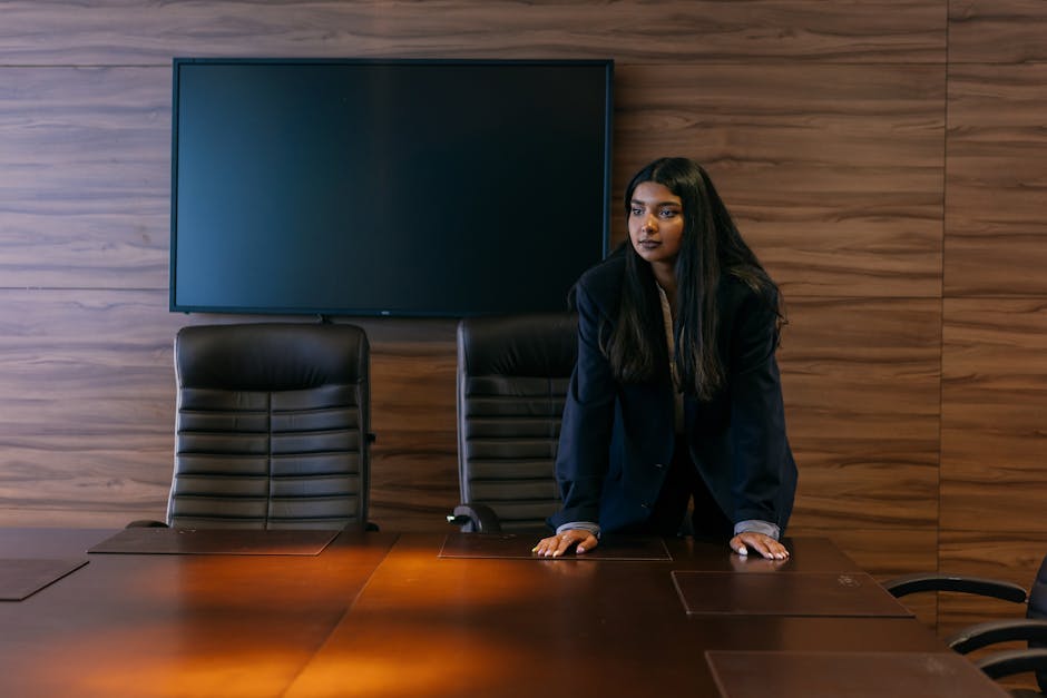 Professional woman in corporate attire standing in a sophisticated boardroom setting
