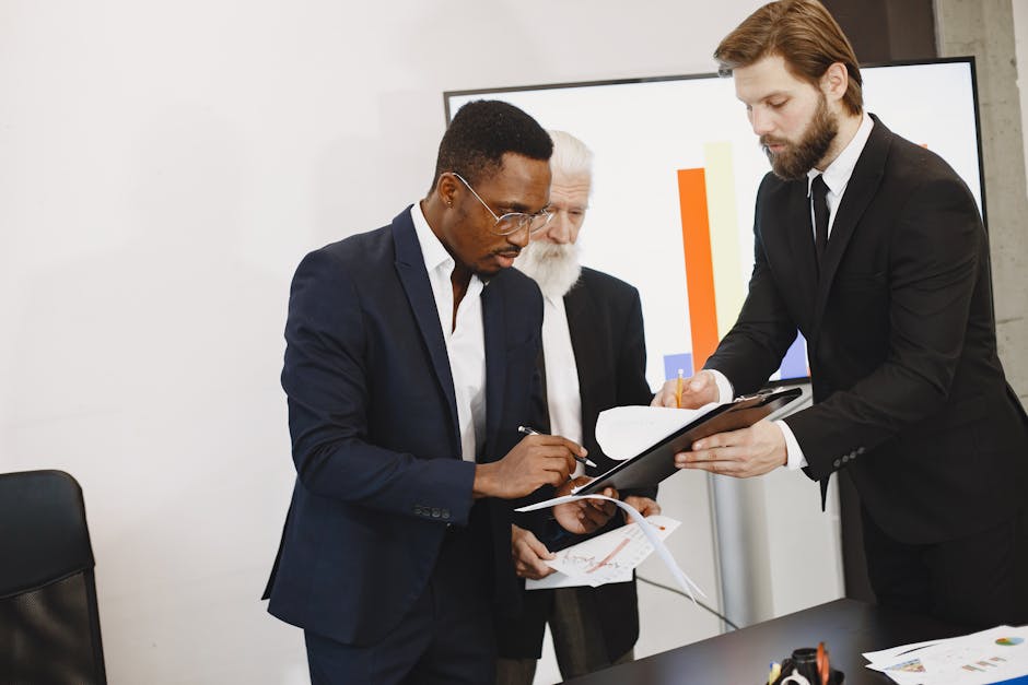 Three businessmen engaged in document signing in a modern office setting